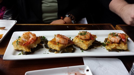 Hers - Shrimp served atop cheddar grit cakes and greens